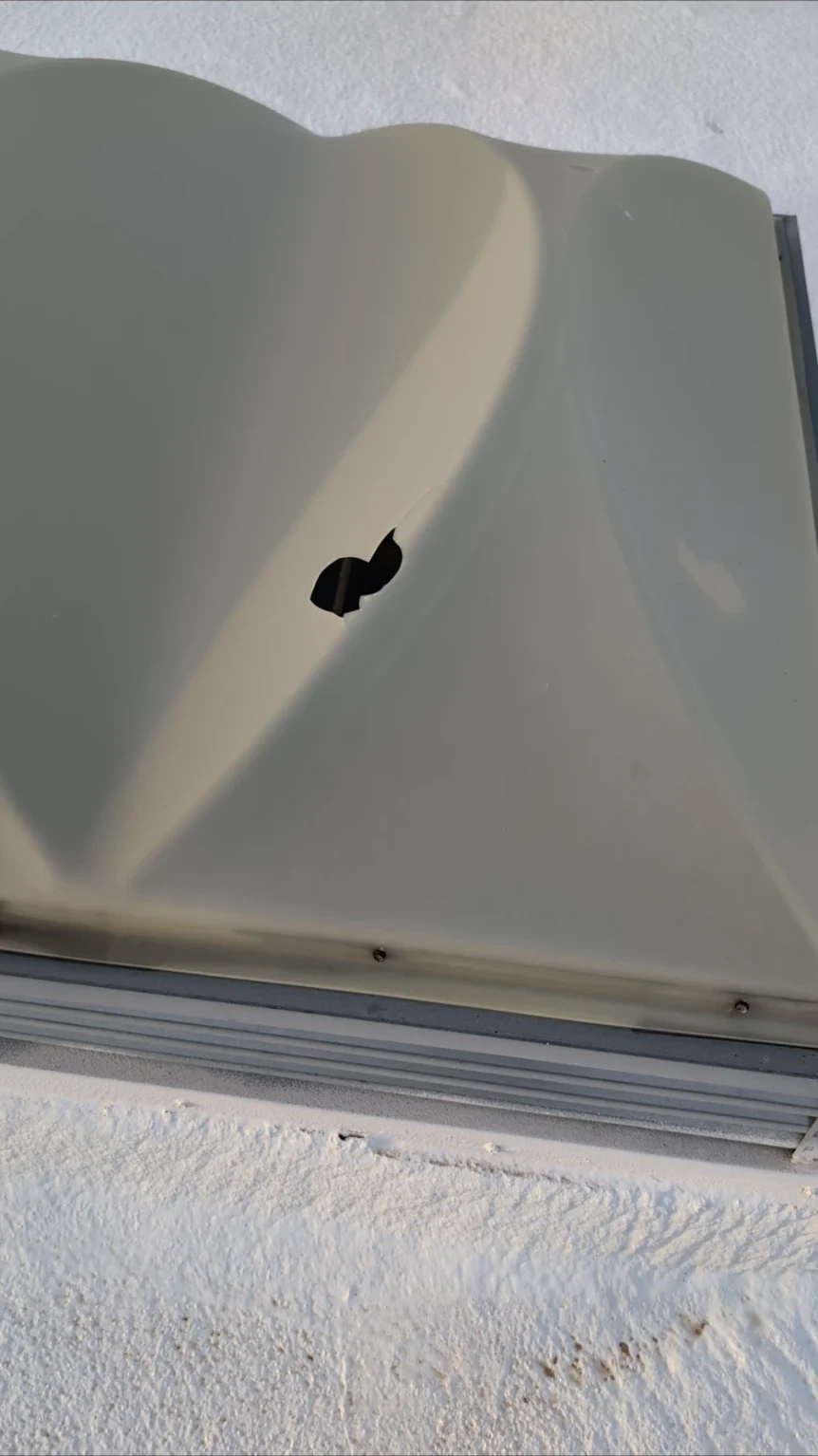 Hail damage has broken a hole through a dome skylight on a commercial building